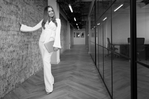 Woman in white suit, modern office hallway